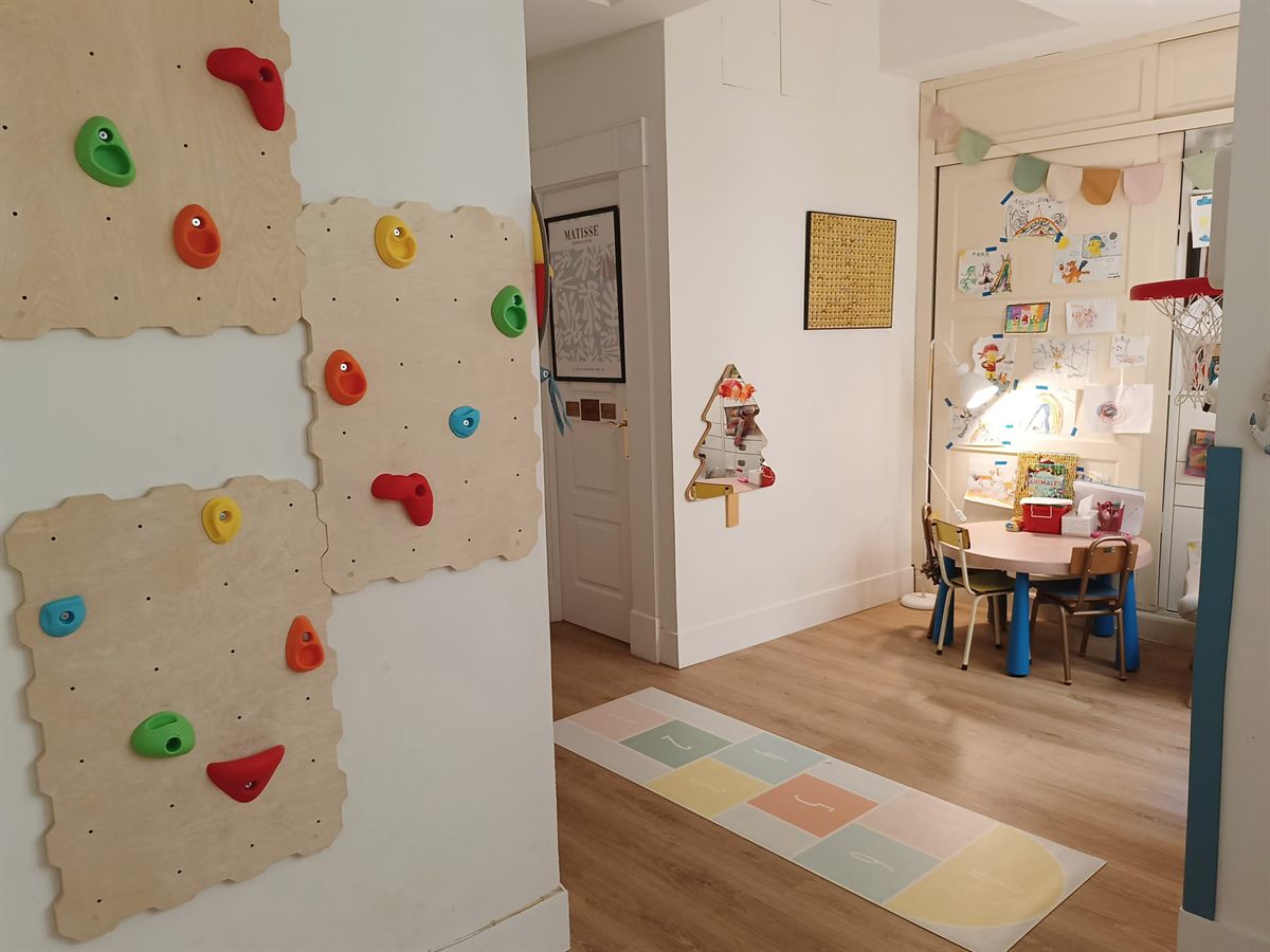 Zona de juego para terapia infantil en aprenderT Chamberí: rocódromo, rayuela y mesa infantil