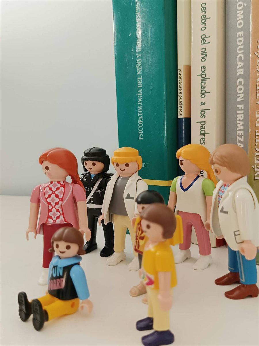 Figuras de una familia con niños y psicólogas delante de libros de psicología infantil en aprenderT Madrid